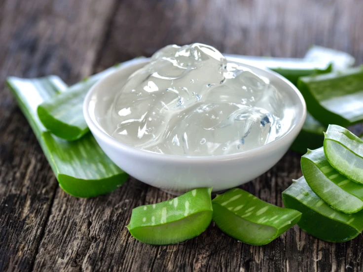 Aloe vera gel and ice cubes arranged on a rustic wooden table, creating a refreshing and natural aesthetic.