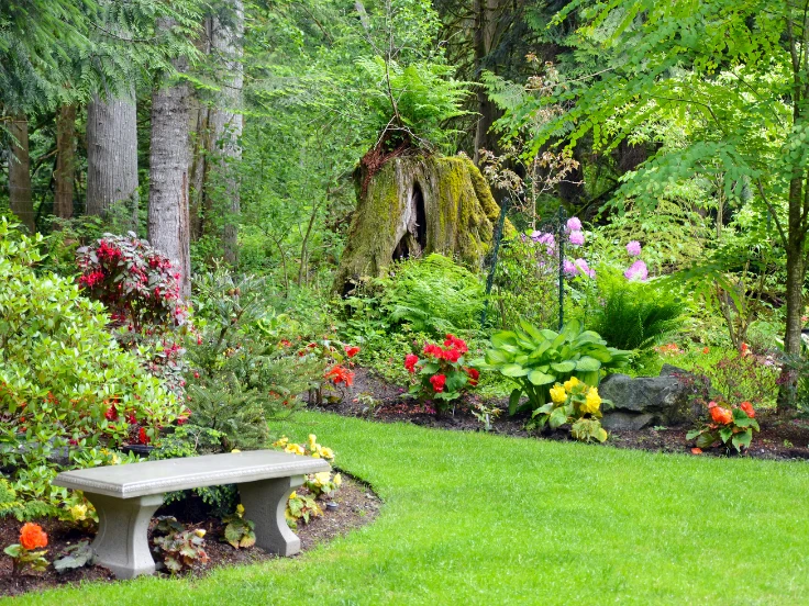 A wooden bench surrounded by colorful flowers in a serene garden setting.