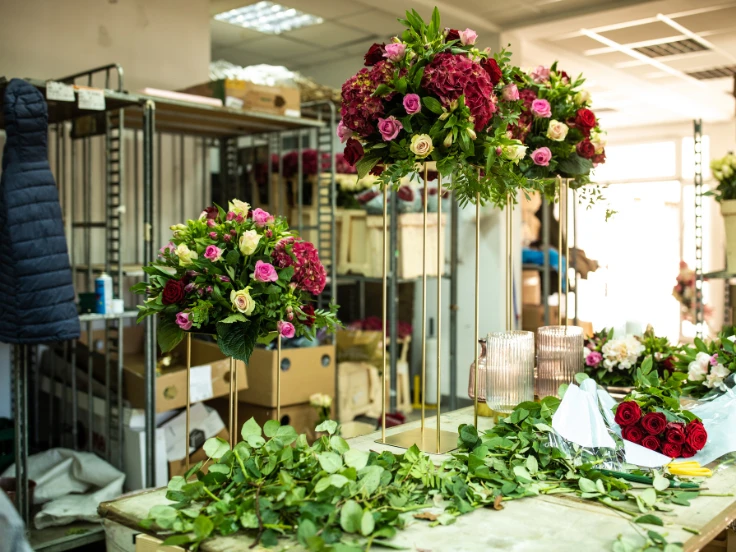 Colorful flowers in various vases are beautifully arranged throughout a charming flower shop.