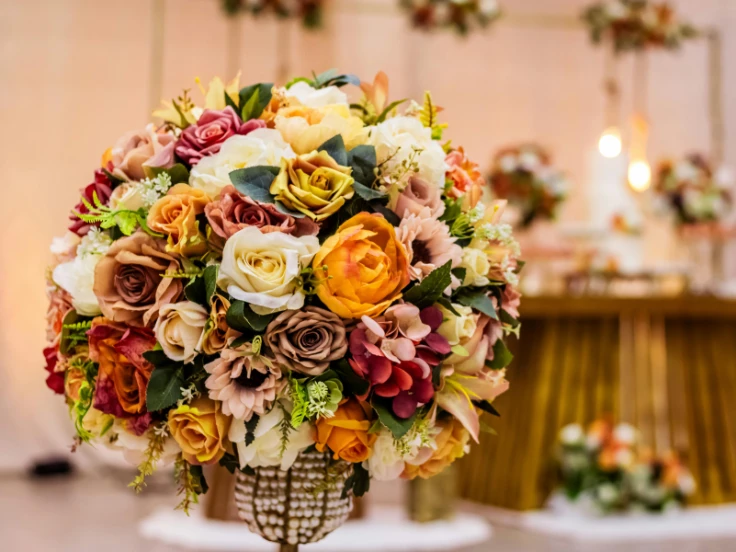 A vibrant flower arrangement in a tall vase, elegantly displayed on a wooden table.