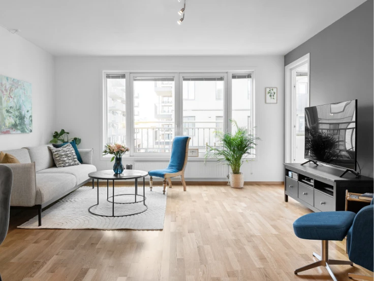 A tidy living room featuring a blue chair and a television against a neutral backdrop.