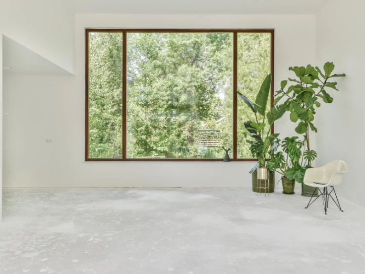 A bright white room featuring a large window and a single chair, creating a serene and open atmosphere.