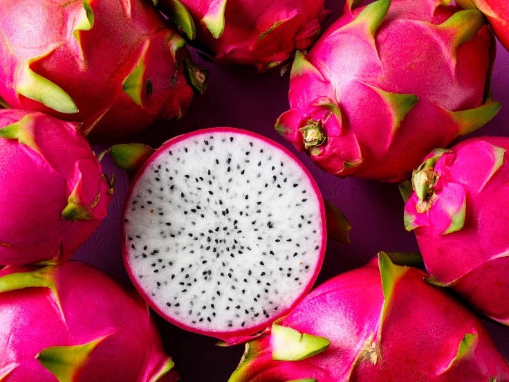 A detailed view of dragon fruit on a striking purple backdrop, highlighting its bright pink skin and green scales.