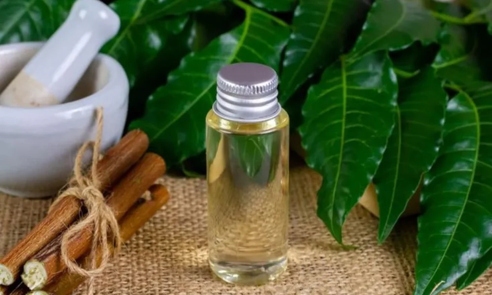 oil with a silver cap is placed on burlap, surrounded by lush green leaves