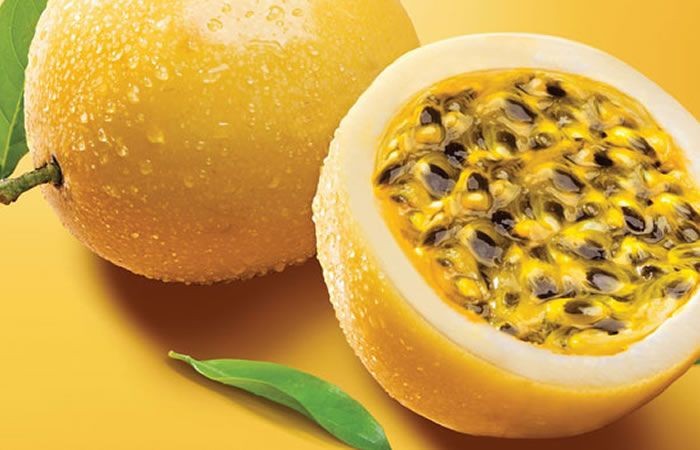 Fresh yellow passion fruit, one whole and one sliced in half.