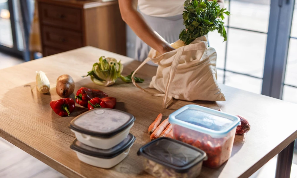 Person organizing fresh vegetables from a cotton market bag onto a wooden kitchen table-Green Living Ideas