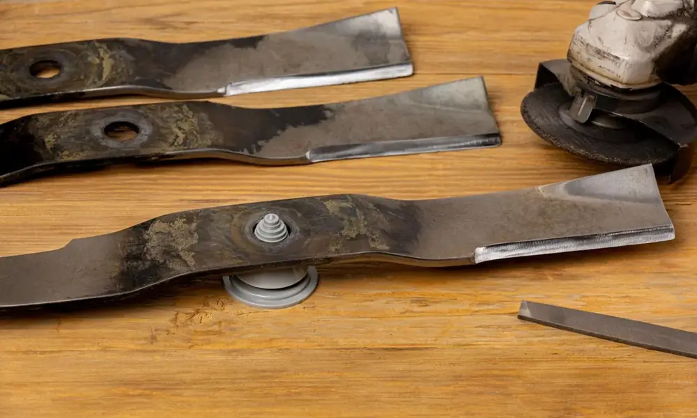 Peeacelily | Lawn Mower Repair: Common Problems and How to Fix Them Lawn mower blades being sharpened on a wooden workbench with a grinder and file.