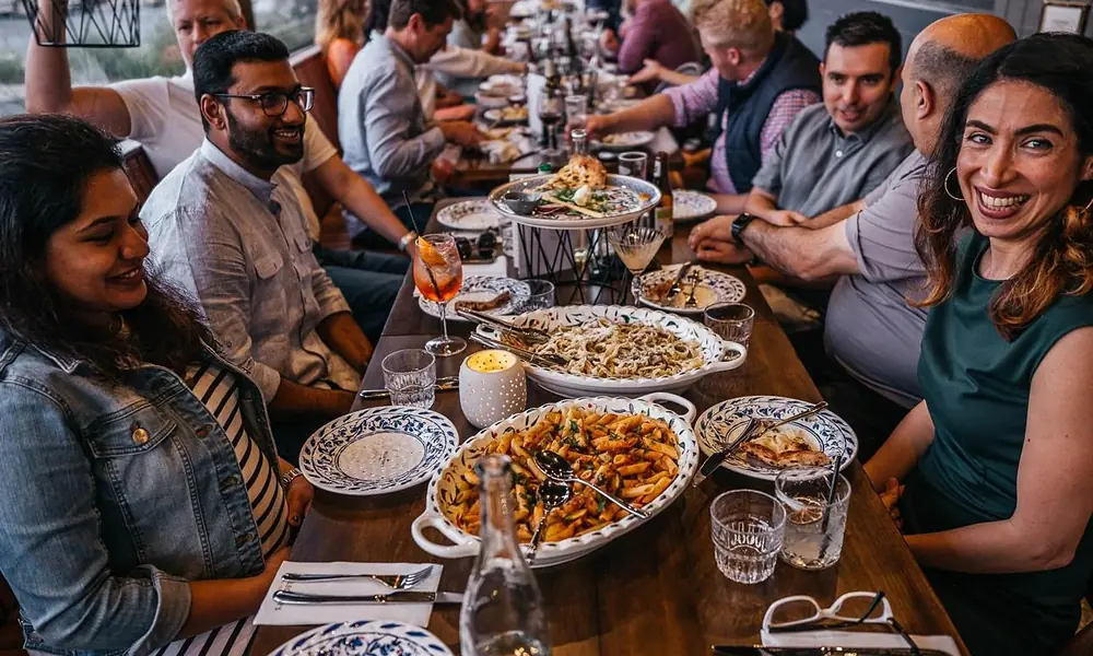 Peeacelily | Olive Garden: A Guide to the Menu, Dining, and Ordering Happy family and friends dining together around a long table filled with shared pasta dishes