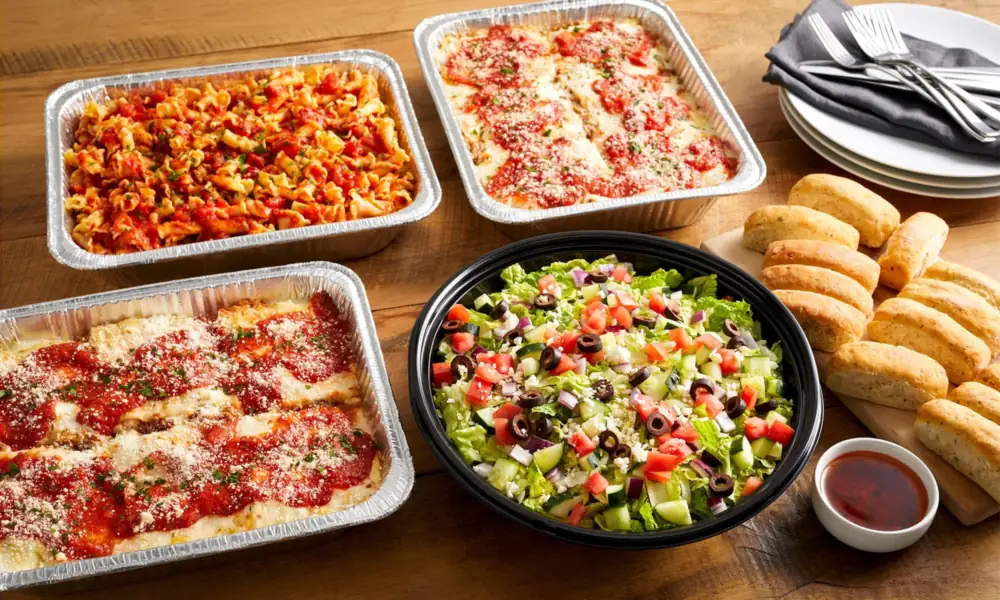 Peeacelily | Olive Garden: A Guide to the Menu, Dining, and Ordering Olive Garden family-style catering trays filled with lasagna, ziti, garden salad, and breadsticks