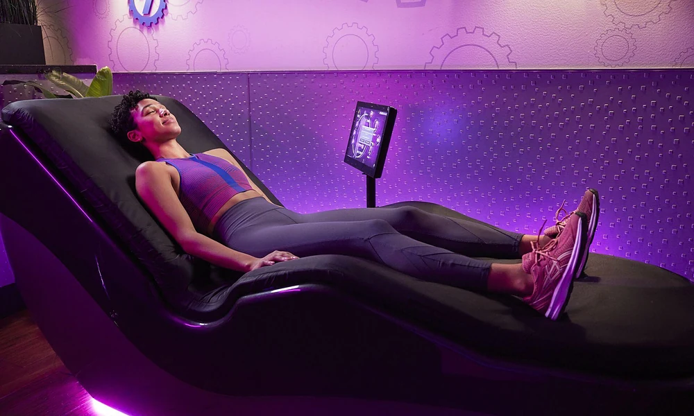 Peeacelily | Planet Fitness: Membership Costs, Equipment, Benefits, and What to Know Member relaxing on a HydroMassage lounge bed in the ambient purple-lit Black Card spa lounge